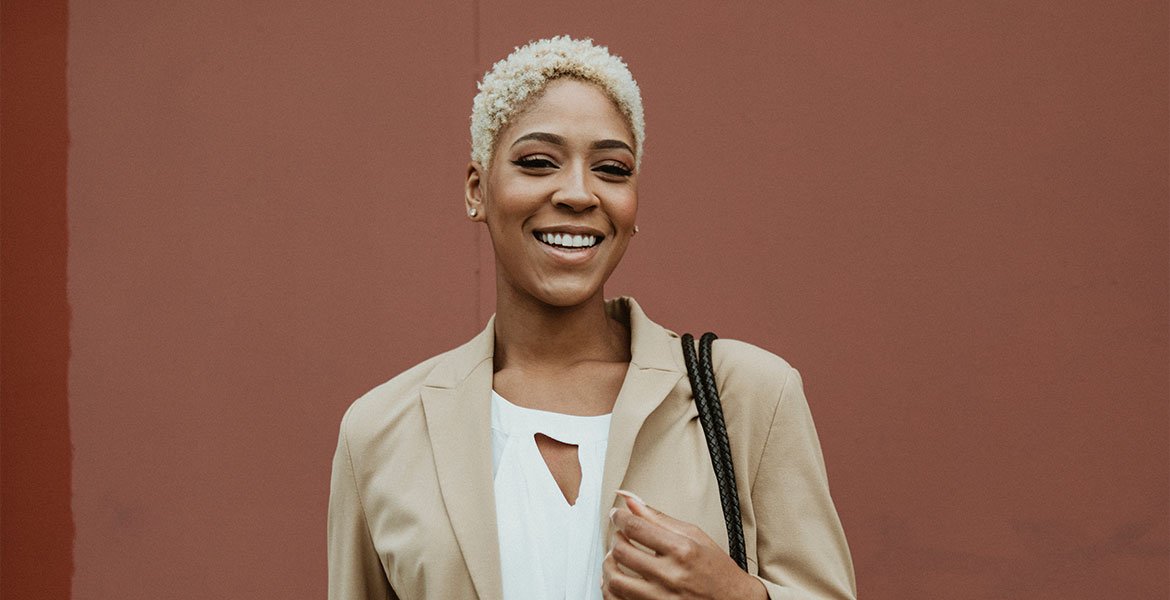 Mulher negra de cabelos curtos platinados sorrindo
